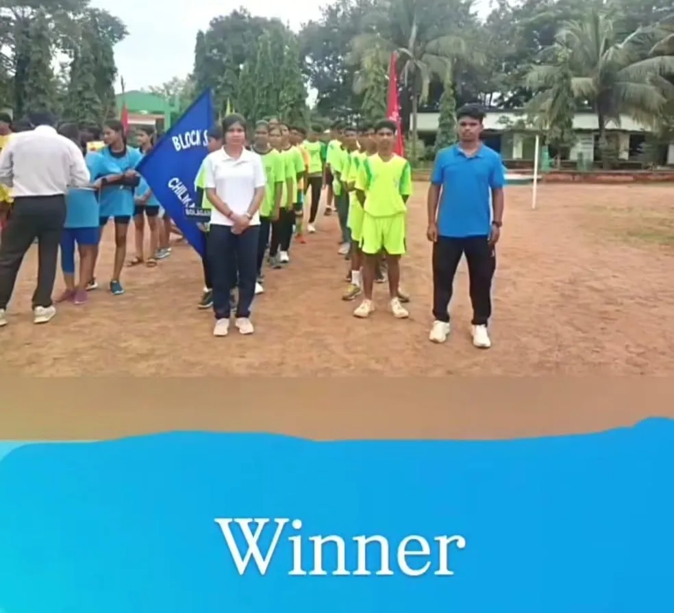 Students and mentors gathered on a sports field with a winner banner.
