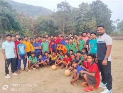 A student sports team and mentors posing together on a field.