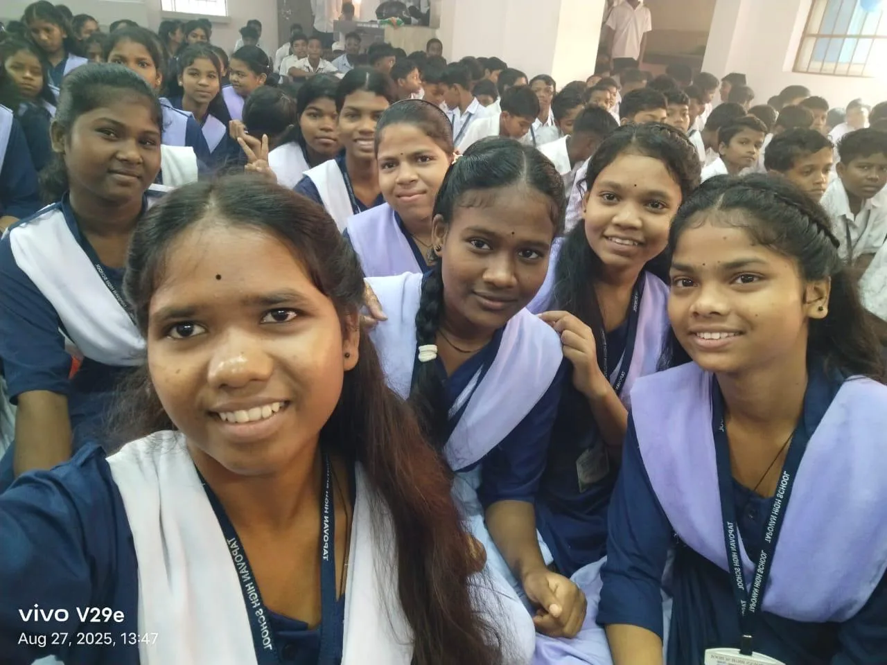 Students in school uniforms smiling together inside a classroom.