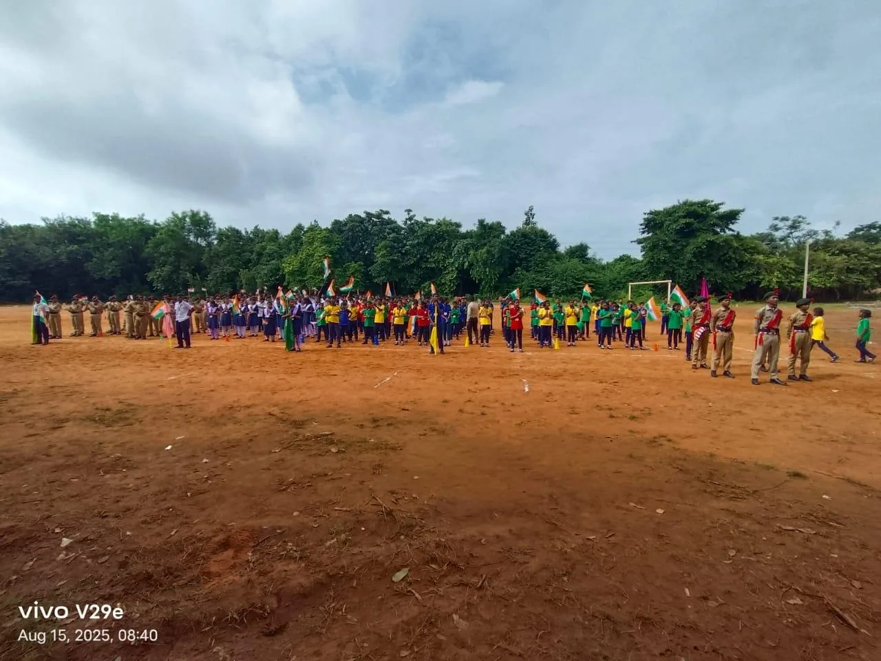Large student groups assembled across an outdoor sports field.