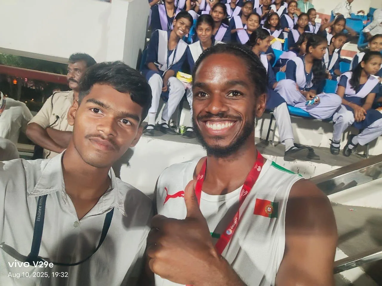 Two event participants smiling for a selfie among students.