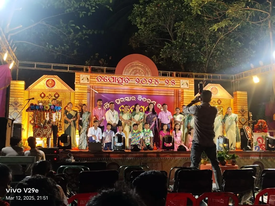 Students and guests gathered on a lit stage for awards at night.