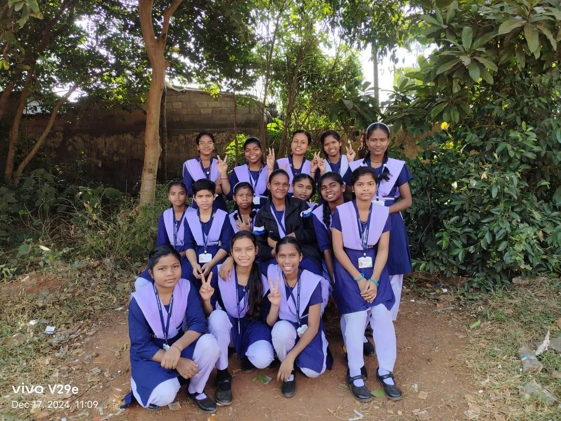 Girl students in uniform posing together under trees