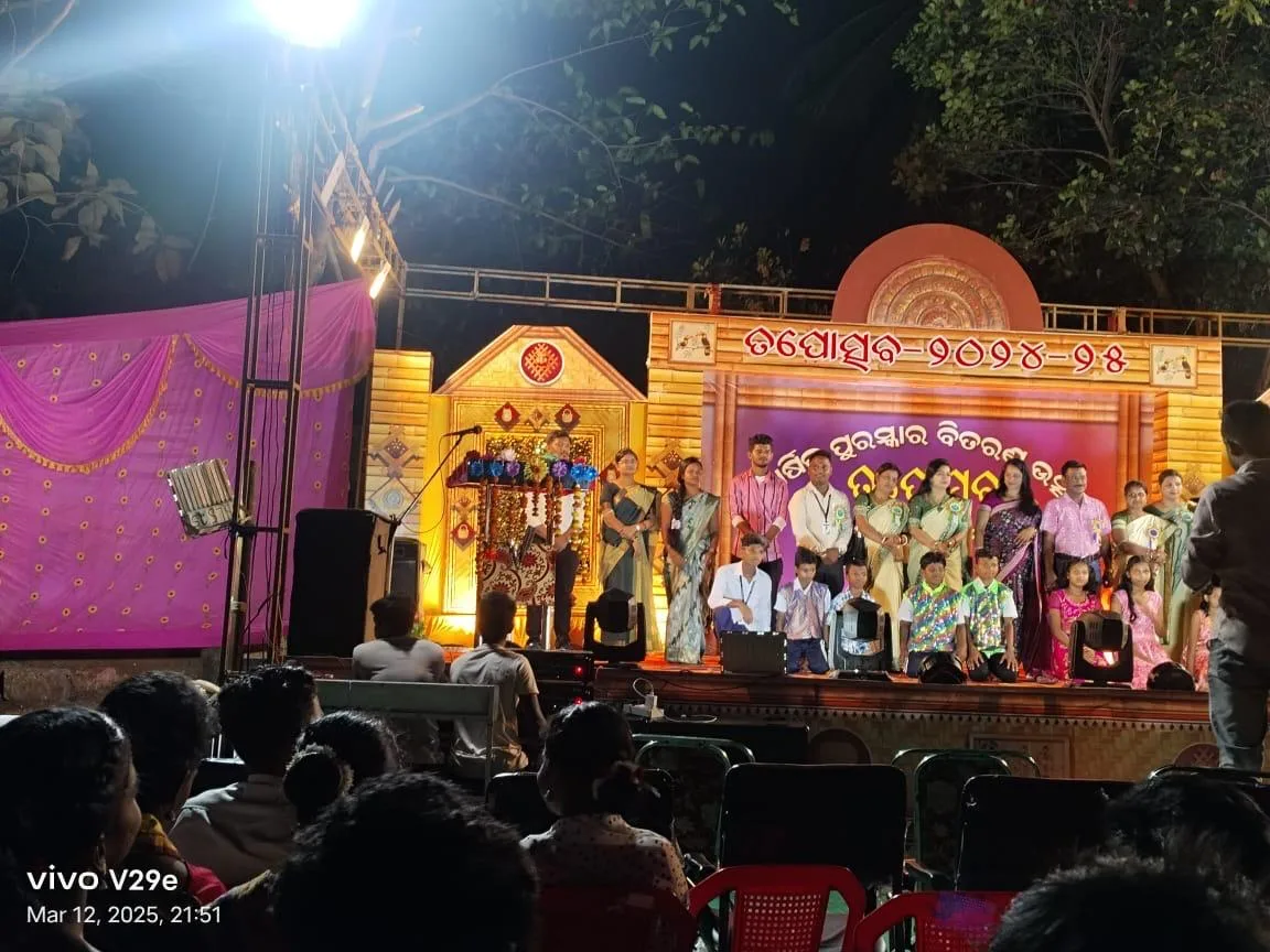 An evening stage program with students and guests under bright lights.